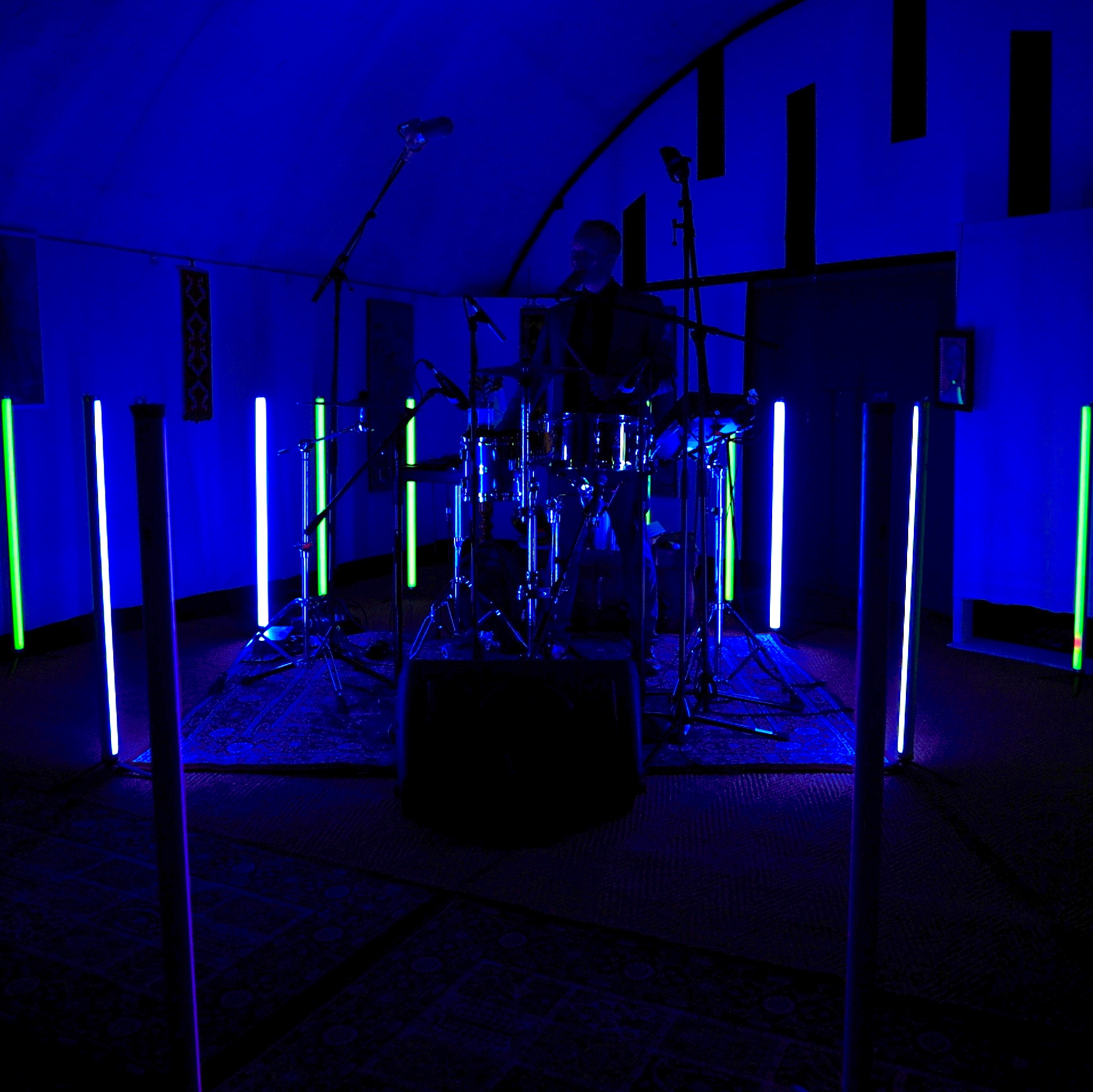 Marc Pell playing a drumkit in a dark room with blue lights