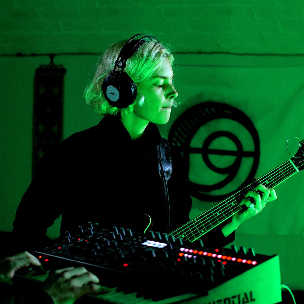 Tara plays guitar against a green backdrop