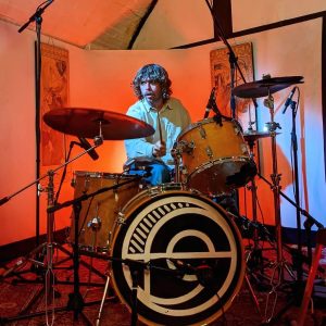 A drummer plays in a dramatic red at arcus sounds studio in east london